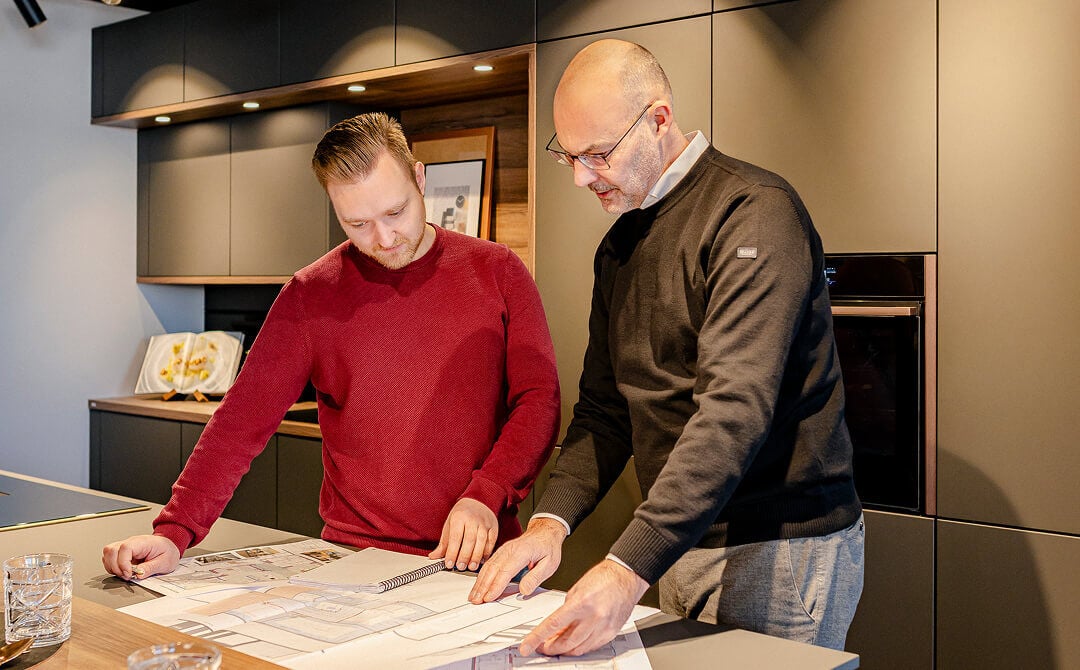 Inhaber des Küchenstudios plant eine Küche für seinen Kunden, Skizzen und Pläne liegen auf dem Tisch.